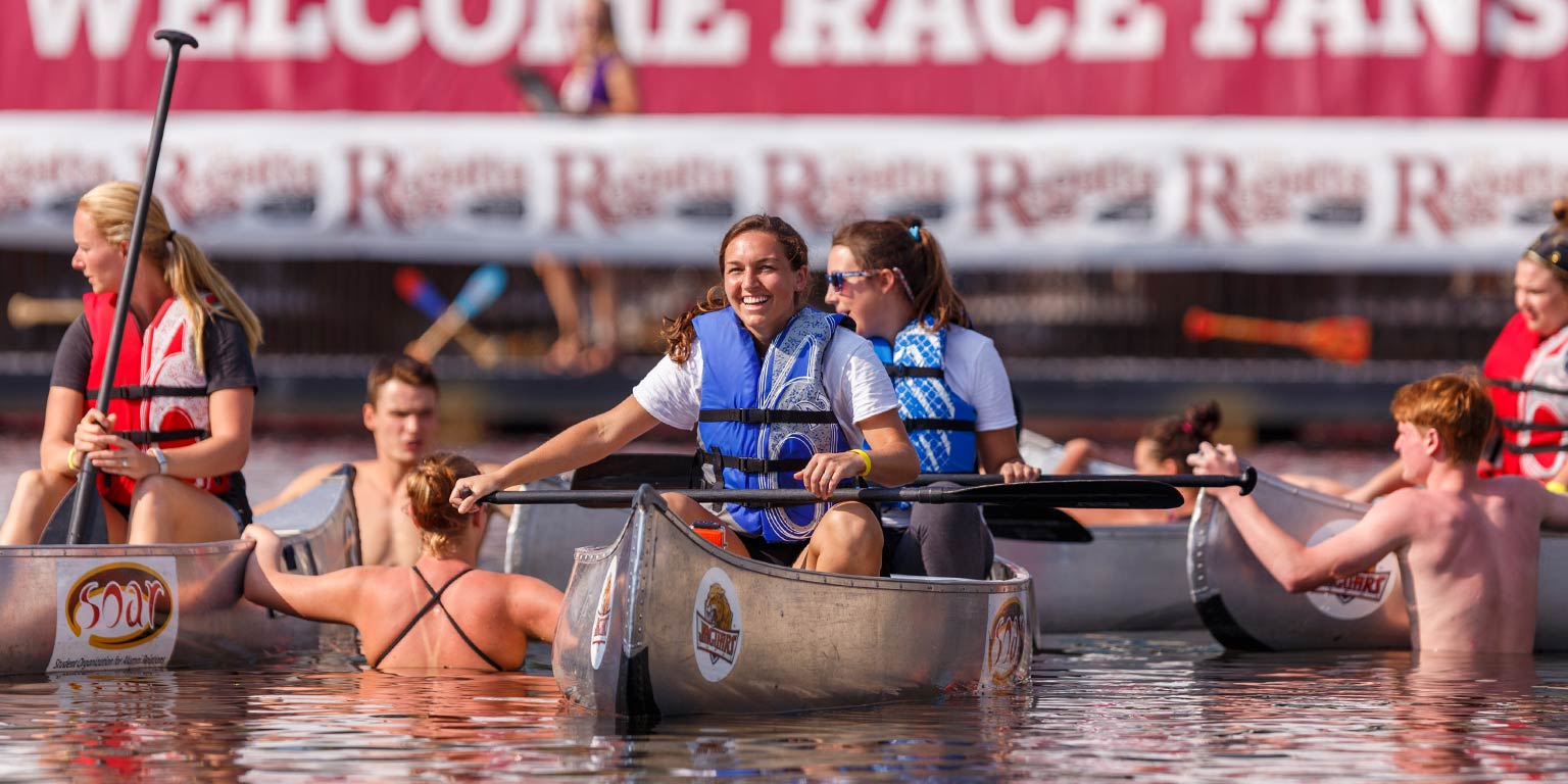 Students at the IUPUI Regatta sit in canoes on the water.