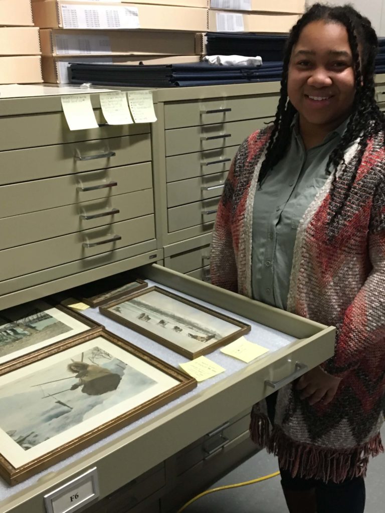 A student works in collection storage during her internship.