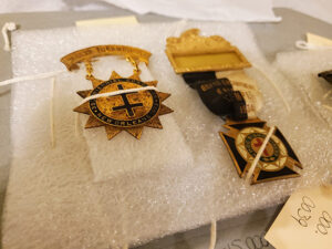 Masonic pins and badges tied to a foam base for archival storage
