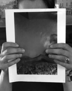 A black and white image of a printed out photo being held my the author with both hands. The photo covers the authors face.