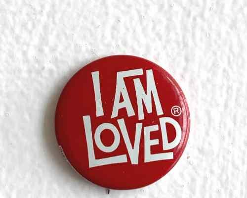 A round red pin with the words "I am loved" in white