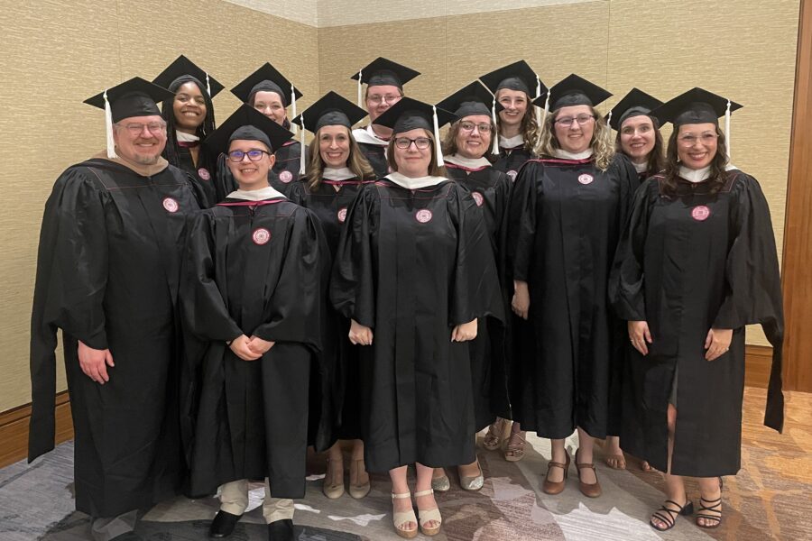 A group of people smiling and wearing graduation regalia