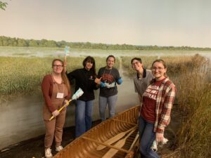 Students and professor cleaning a boat in a museum. 